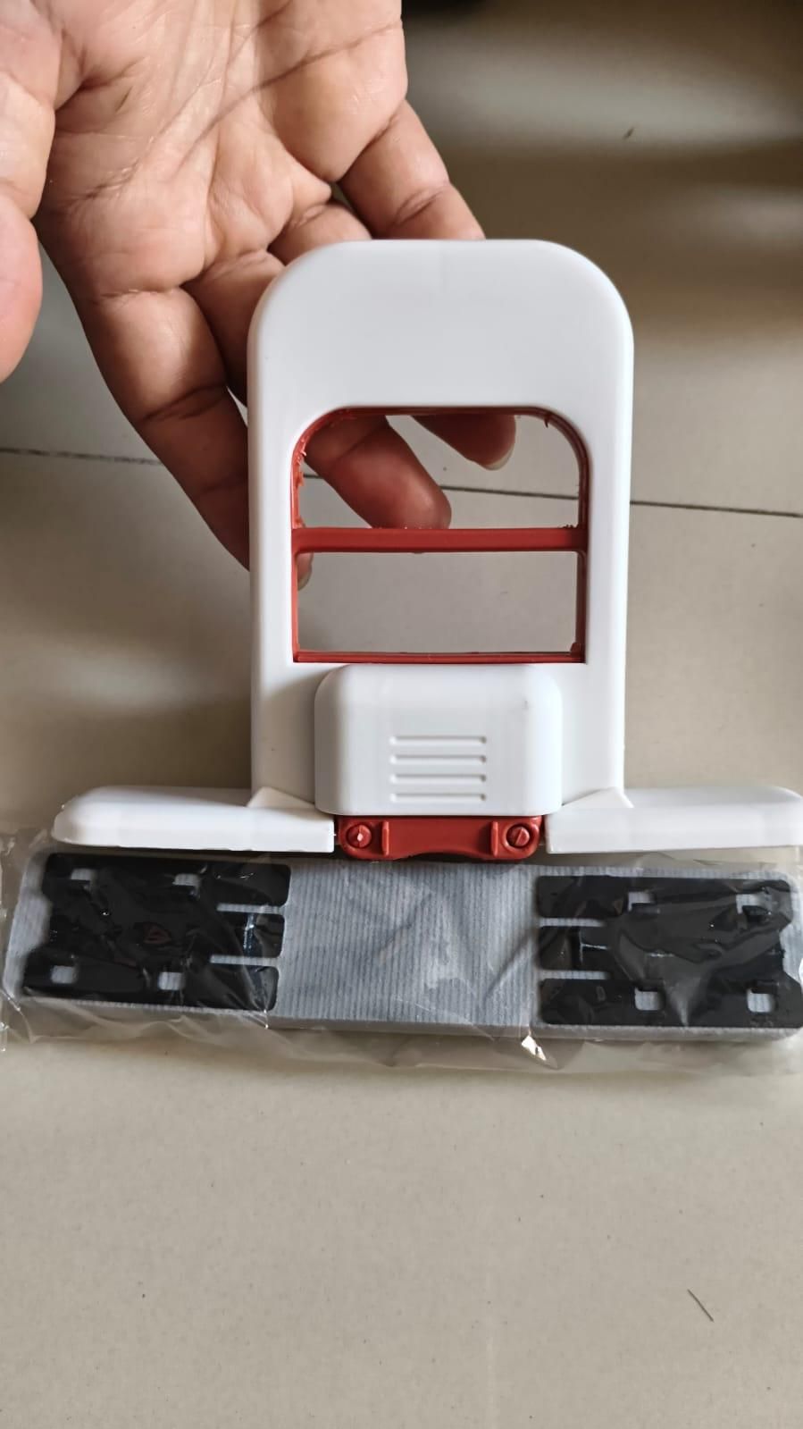 Hand holding a white and red tool with a clear plastic cover on a neutral background