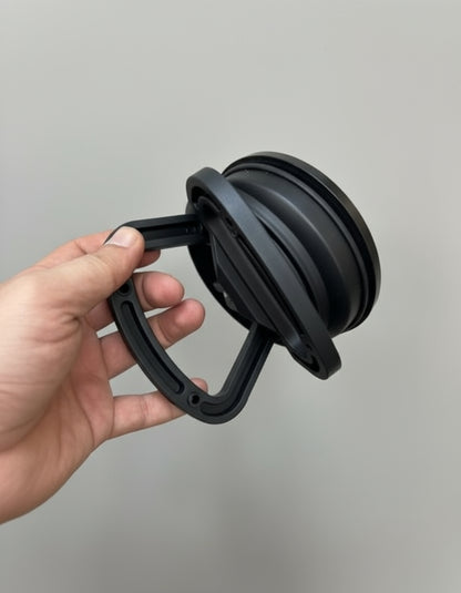 Black adjustable stand held by a hand against a gray background